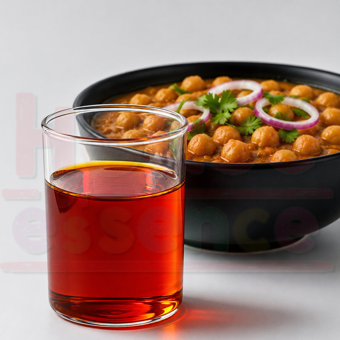 Glass of red juice with a bowl of chickpea curry on a white background