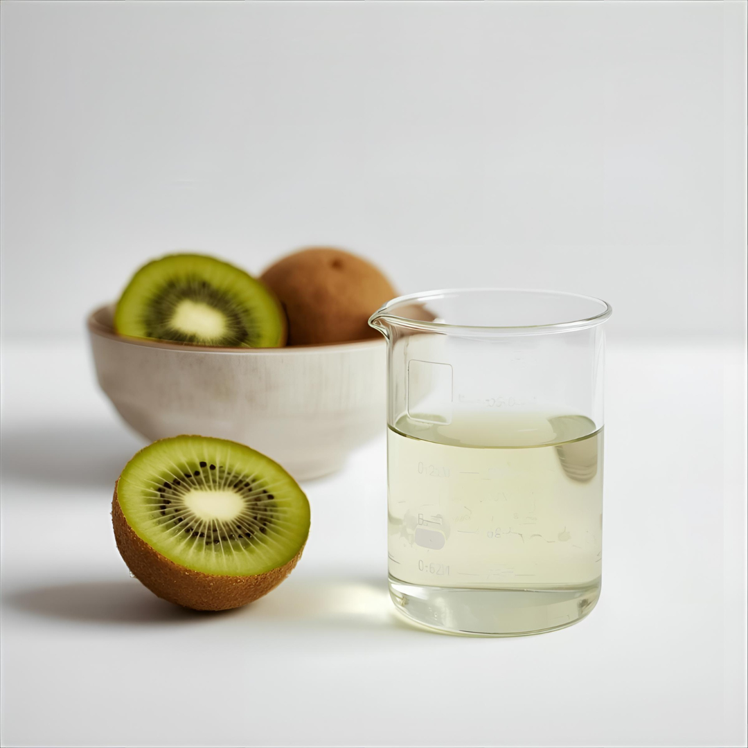 Glass of liquid next to a bowl of kiwis on a white background