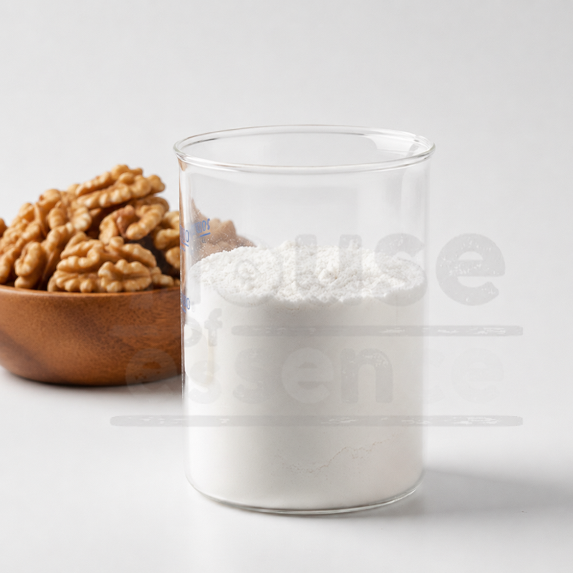 Glass container with white powder next to a wooden bowl of walnuts on a light background